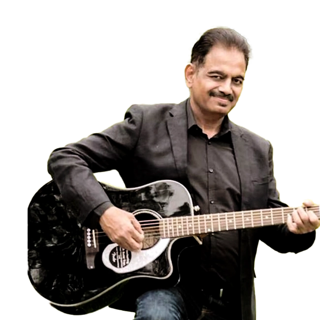 Aamir Saleem in a black suit playing a black acoustic guitar.