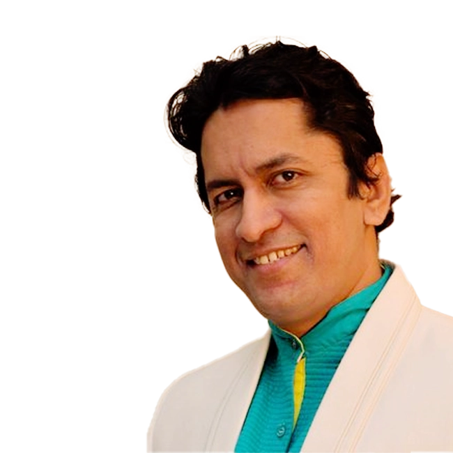 Alok Katdare, an Indian singer, smiling and wearing a turquoise shirt with a white jacket.