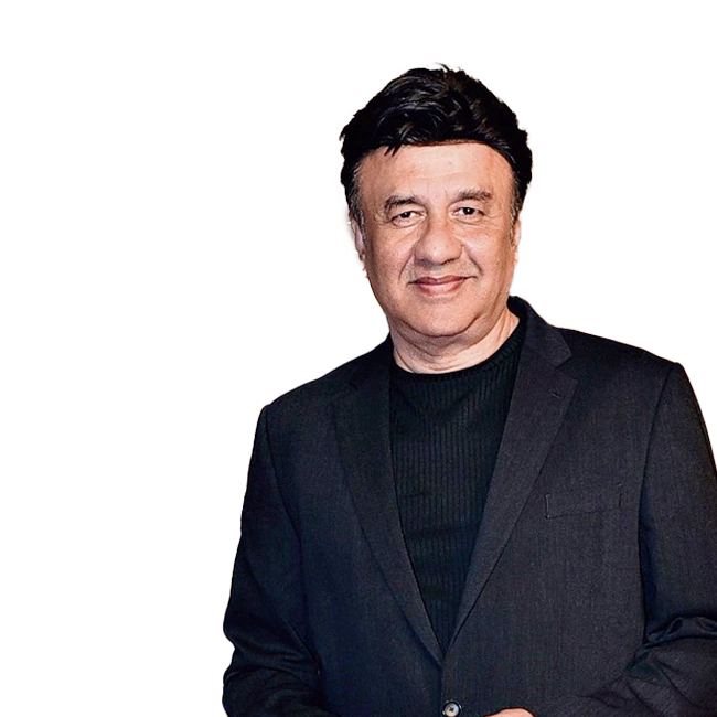 Anu Malik wearing a black suit and smiling