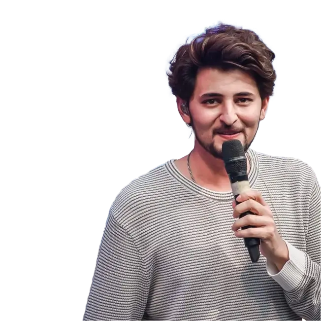 Darshan Raval wearing a striped sweater, holding a microphone and smiling.