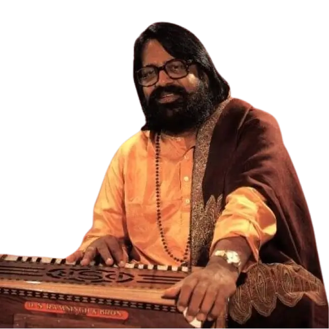 Hari Om Sharan in traditional attire, sitting with a harmonium.