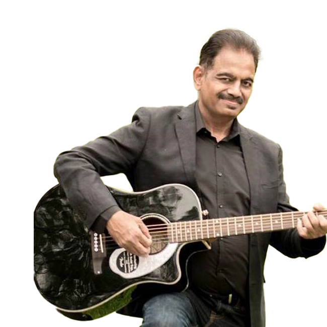 Aamir Saleem in a black suit playing a black acoustic guitar.