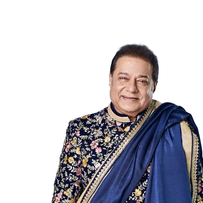 Anup Jalota smiling, wearing an ornate traditional outfit with a blue shawl.