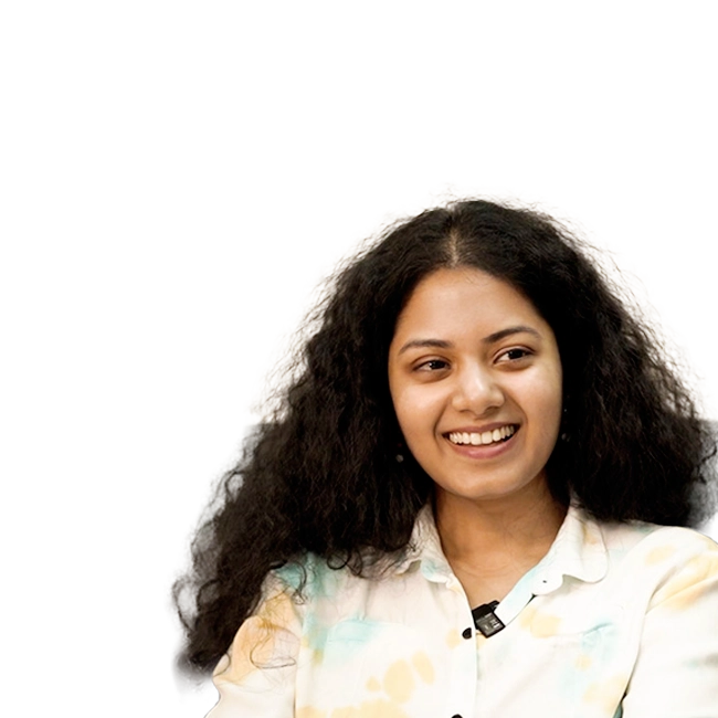 Anwesha Dattagupta smiling with long curly hair, wearing a light-colored shirt.